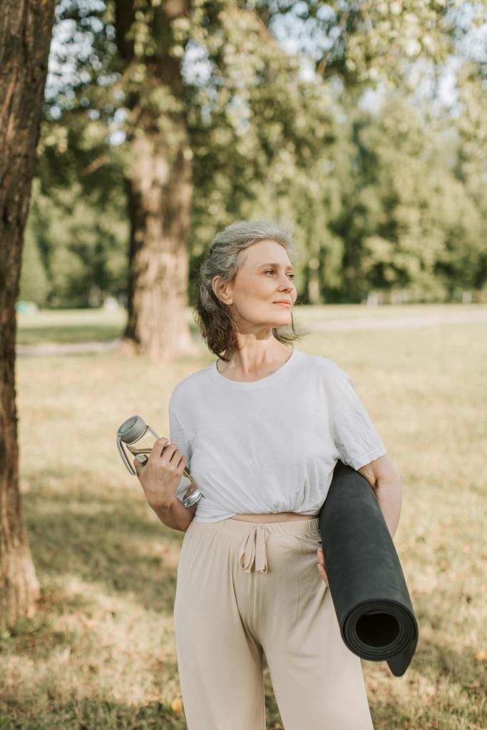 Woman holding water bottle and yoga mat